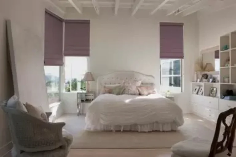 Roman Blinds A Bright Bedroom With A White Bed, White Built In Shelving, And Purple Roman Shades
