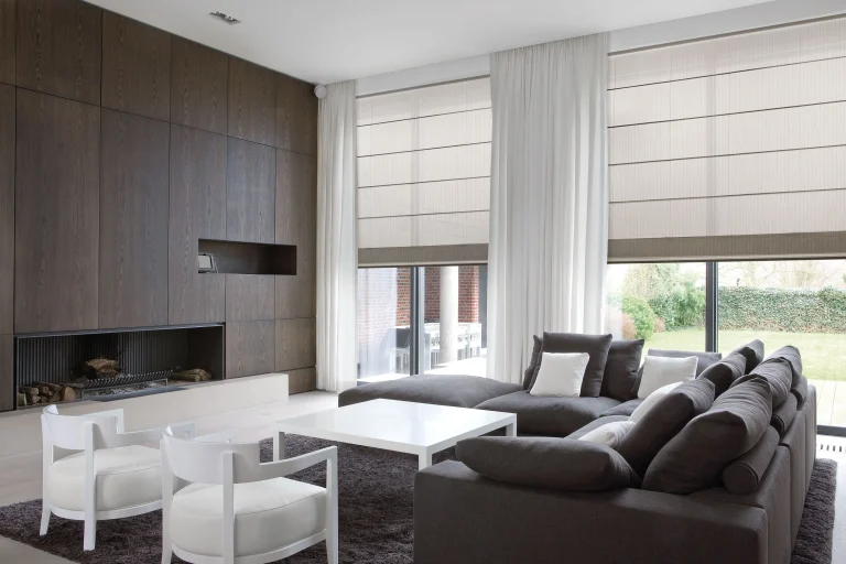 Roman Blinds A Modern Living Room With Dark Wood Paneling, A Fireplace, And A Sectional Sofa Features Large Windows With Roman Shades